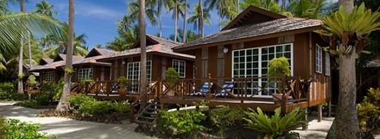 Row of timber chalets with verandahs and sun loungers facing the sand at Sipadan-Mabul Resort (placeholder, to recheck when the photo is replaced)