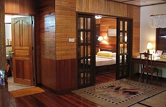 Suite chalet at Sipadan-Mabul Resort: wood-panelled sitting area with glazed doors open to the bedroom (placeholder, to recheck when the photo is replaced)